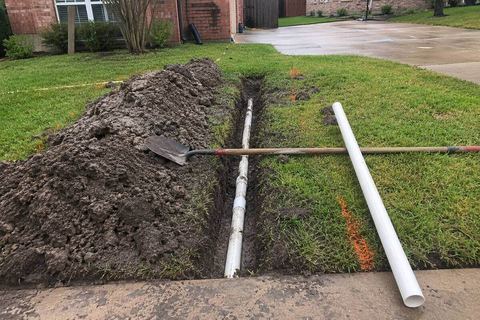 Trench across a lawn exposing a sewer line