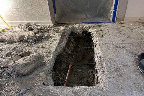 Concrete floor cut open to reach a leaking pipe under a slab